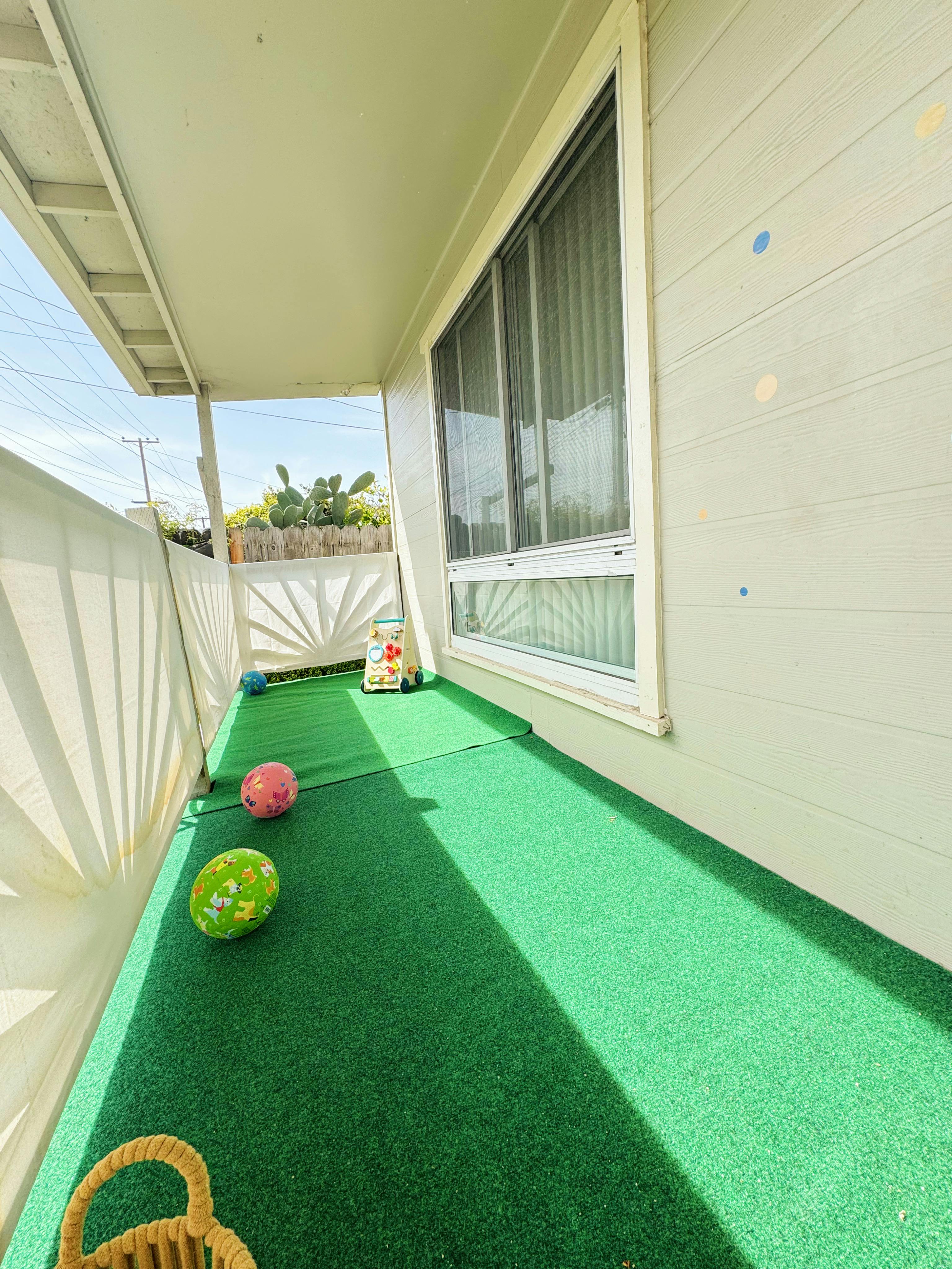 Porch with green turf and several balls