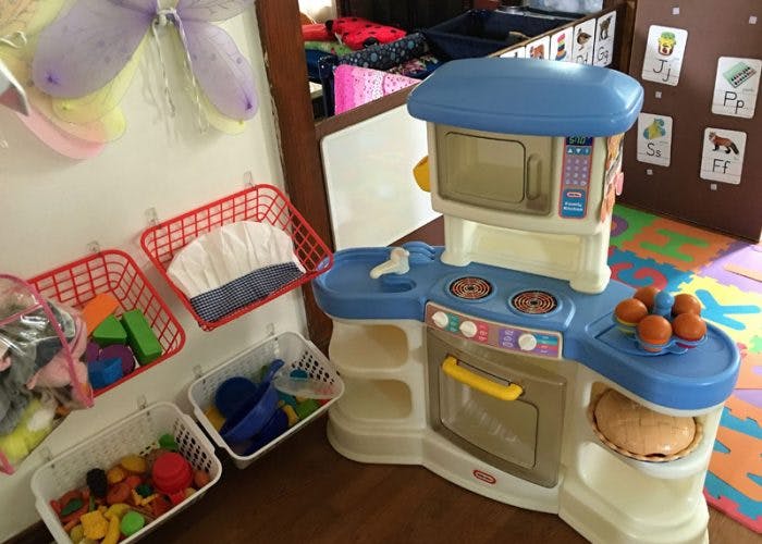 Toy kitchen set with baskets of play food and learning items