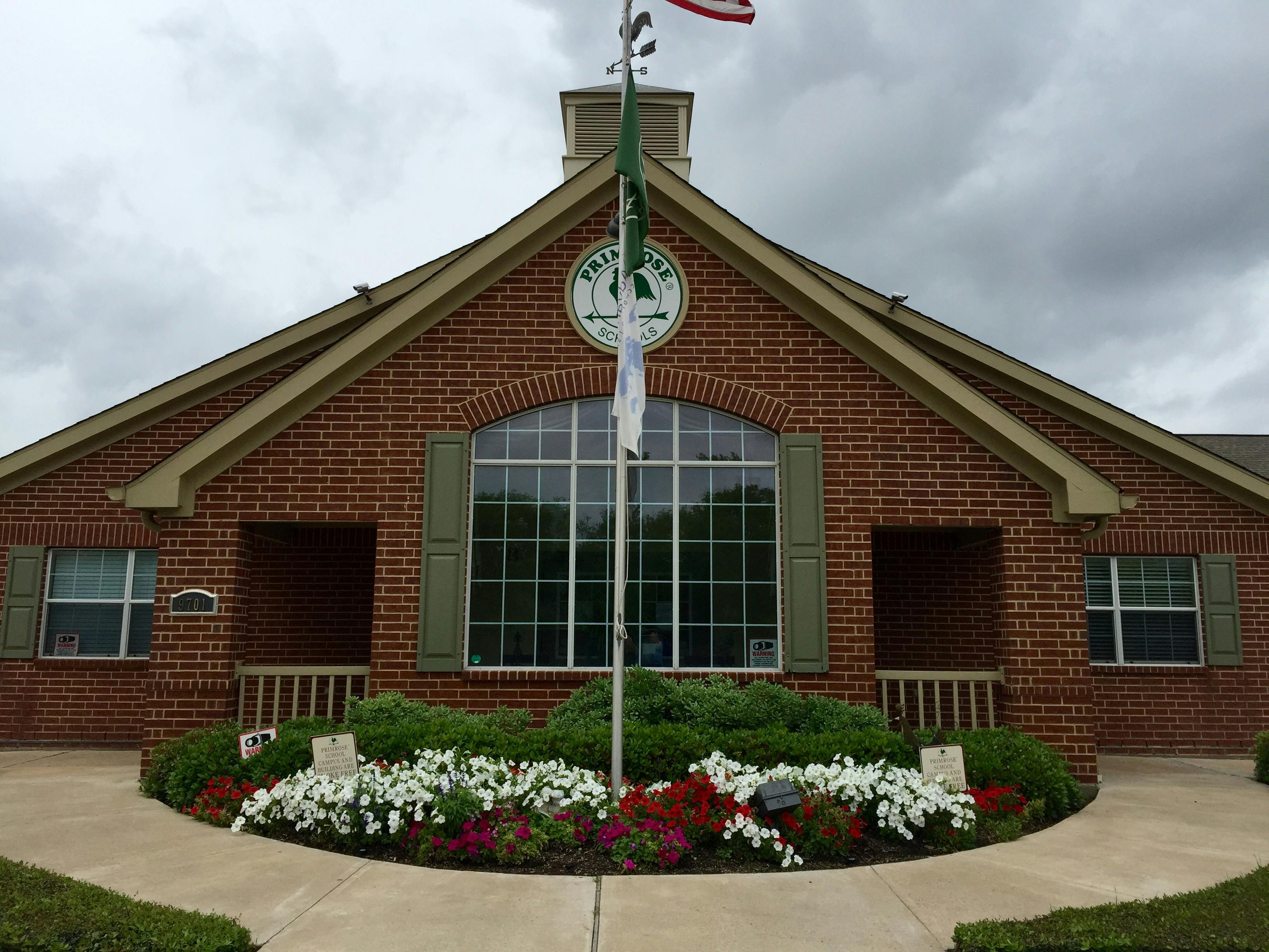 Brick building with a large arched window and a flagpole in front