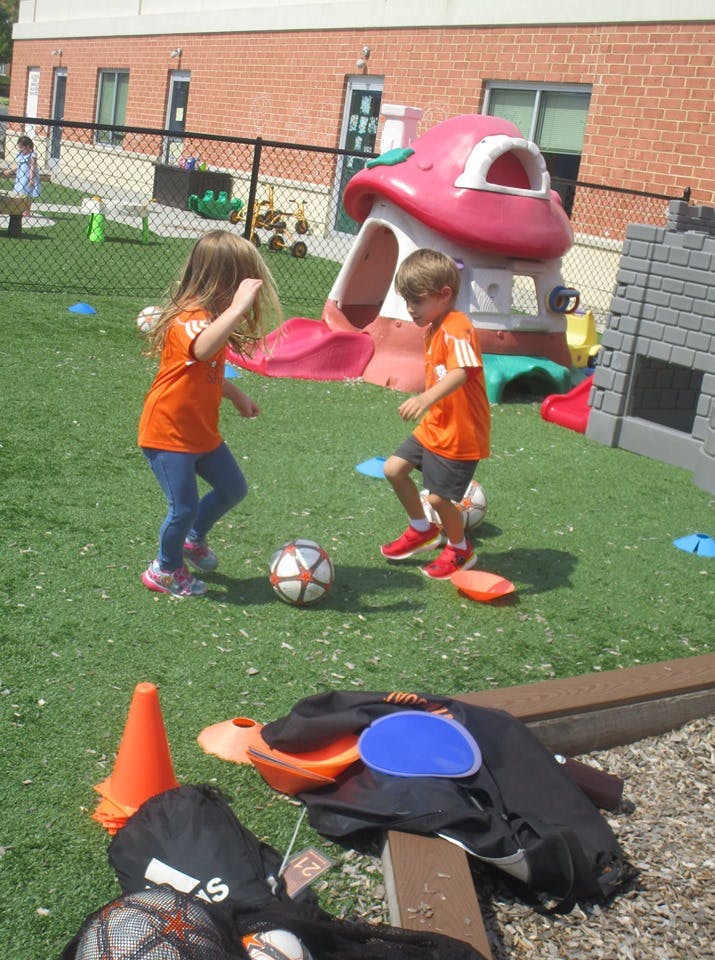 Two children playing soccer on a grassy field
