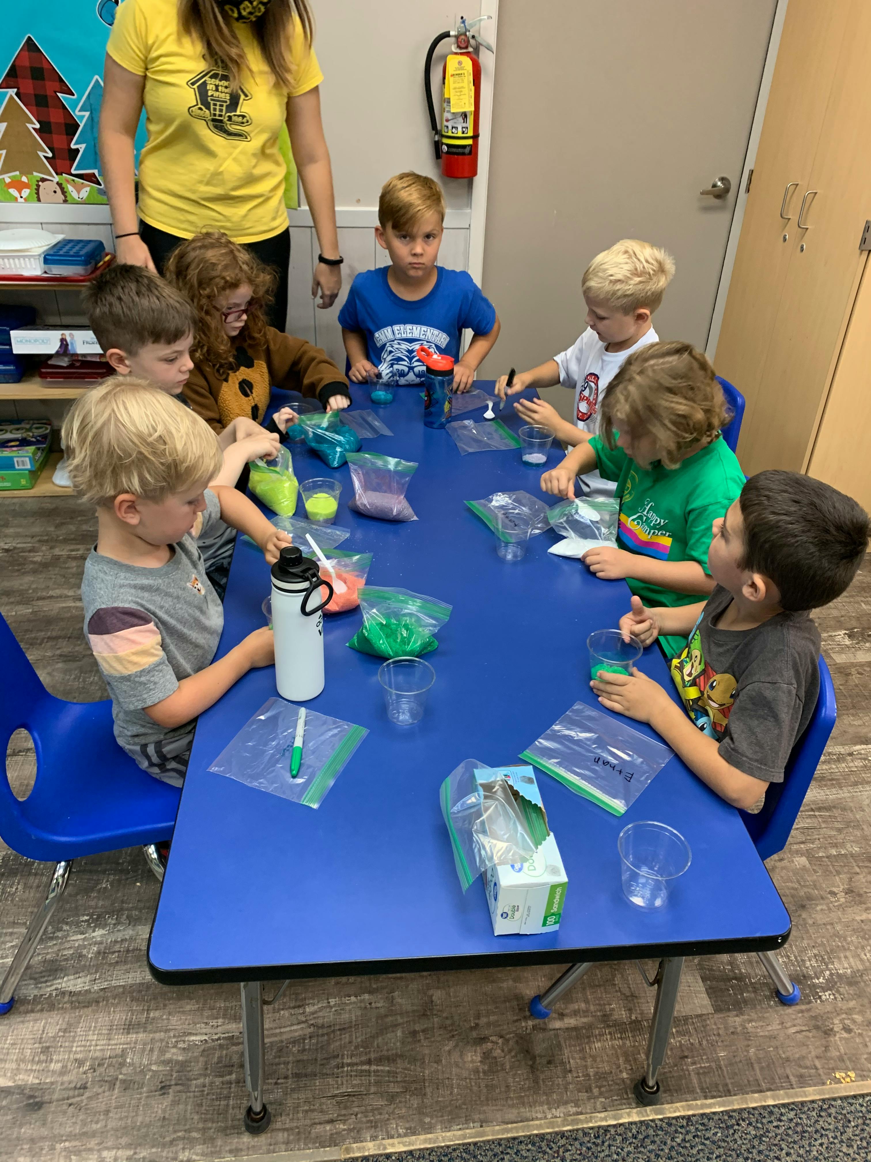 Children and an adult at a table with craft supplies