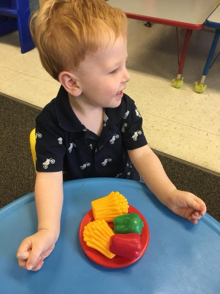 Child at a table with toy food