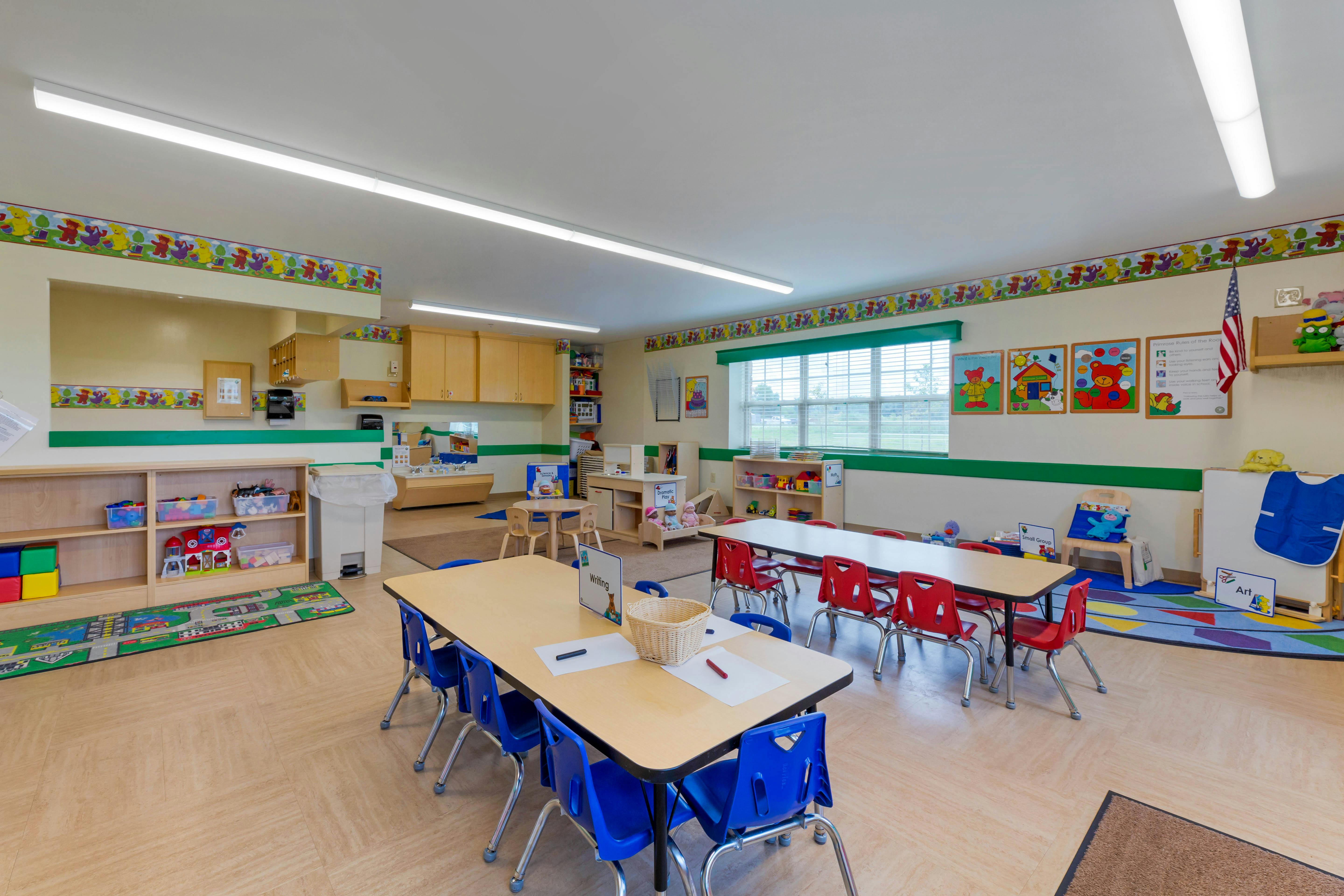 An empty kindergarten classroom with small tables and chairs
