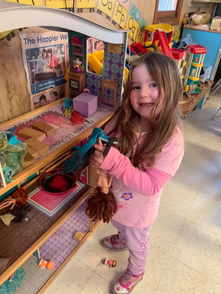 Child holding a doll in a play area