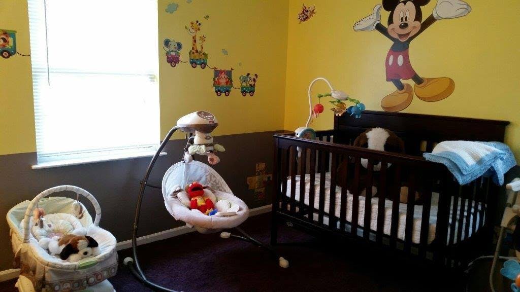 Nursery room with a crib, baby swing, and bassinet