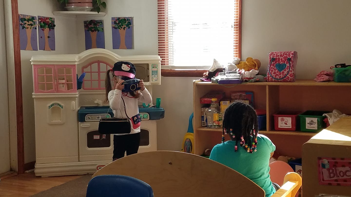 Child playing with toy camera in a play kitchen