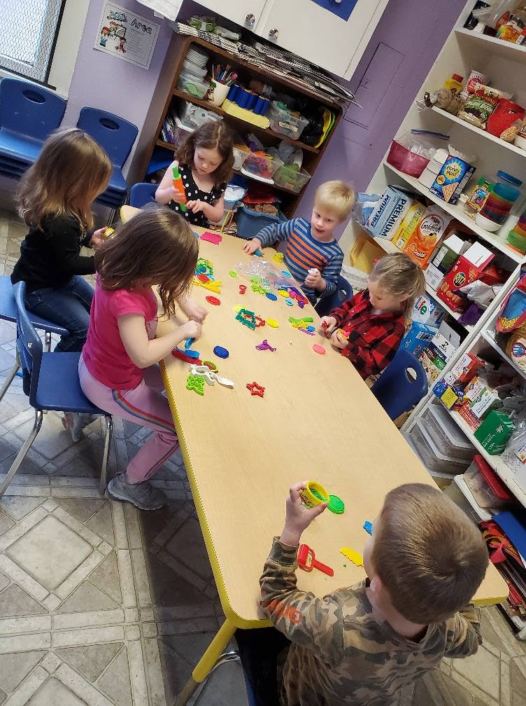Children playing with colorful shapes at a table