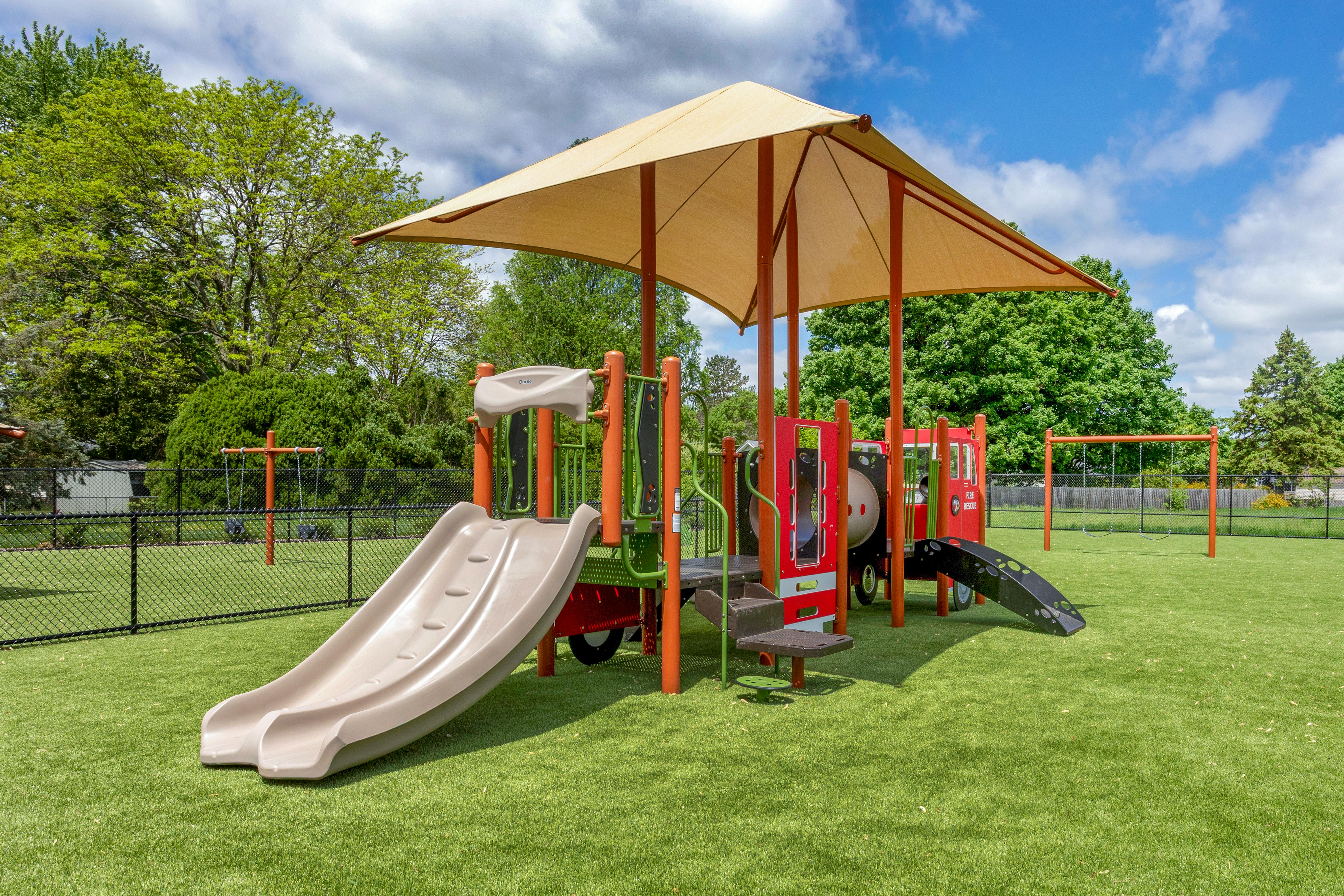 Playground with slides, fire truck themed climbing structure, and swings