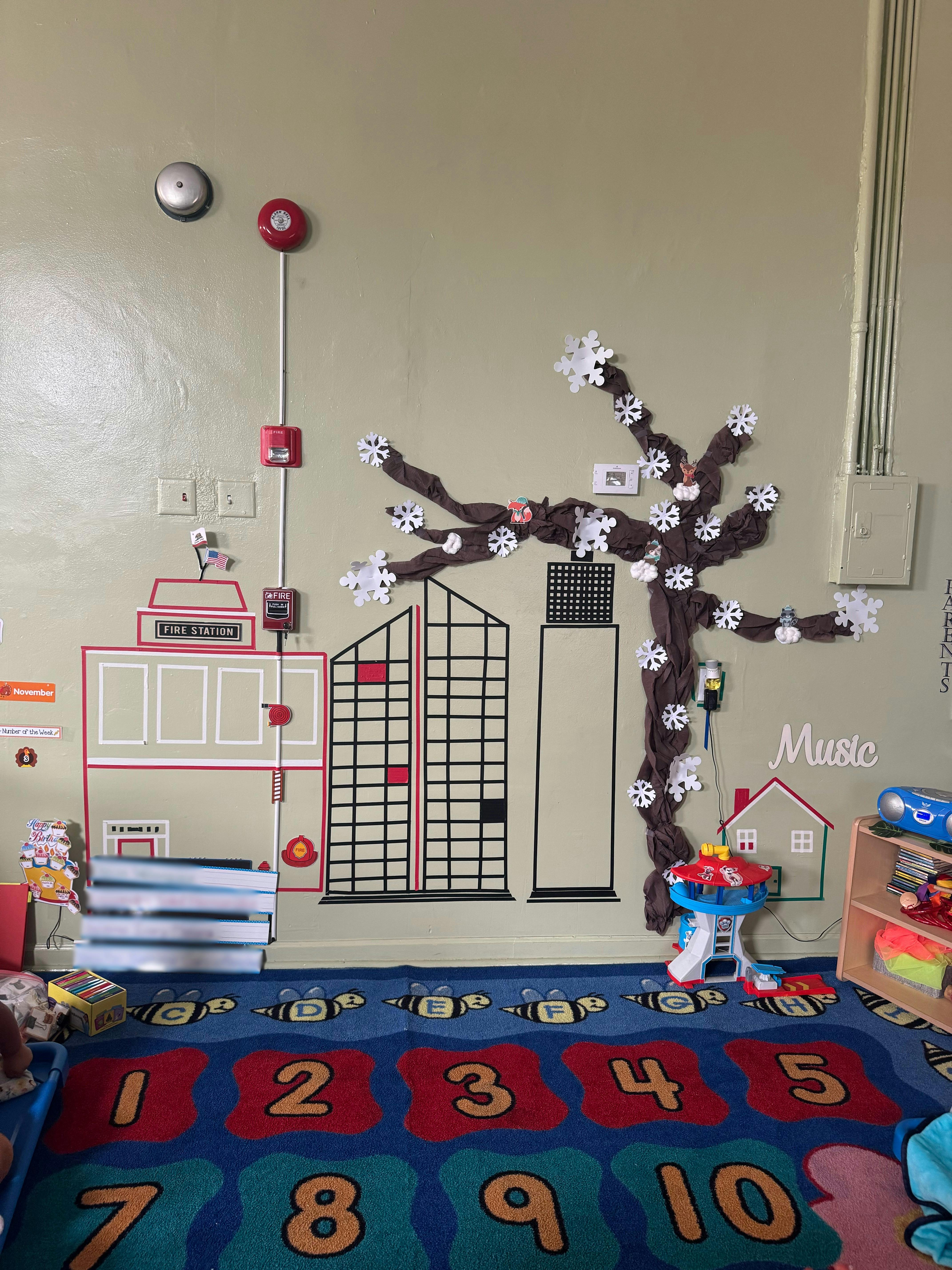 Wall decorated with a city skyline, a tree, and a number rug on the floor