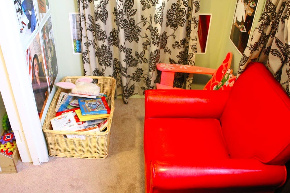 Wicker basket filled with books next to a red armchair