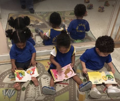 Children sitting on a rug reading books