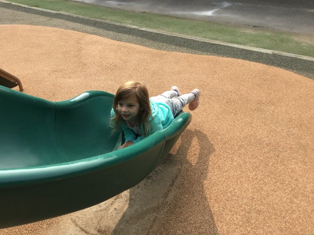 Child lying on a green slide on a playground