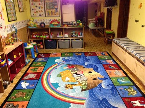 Playroom with a colorful Noah's Ark rug and shelves of toys