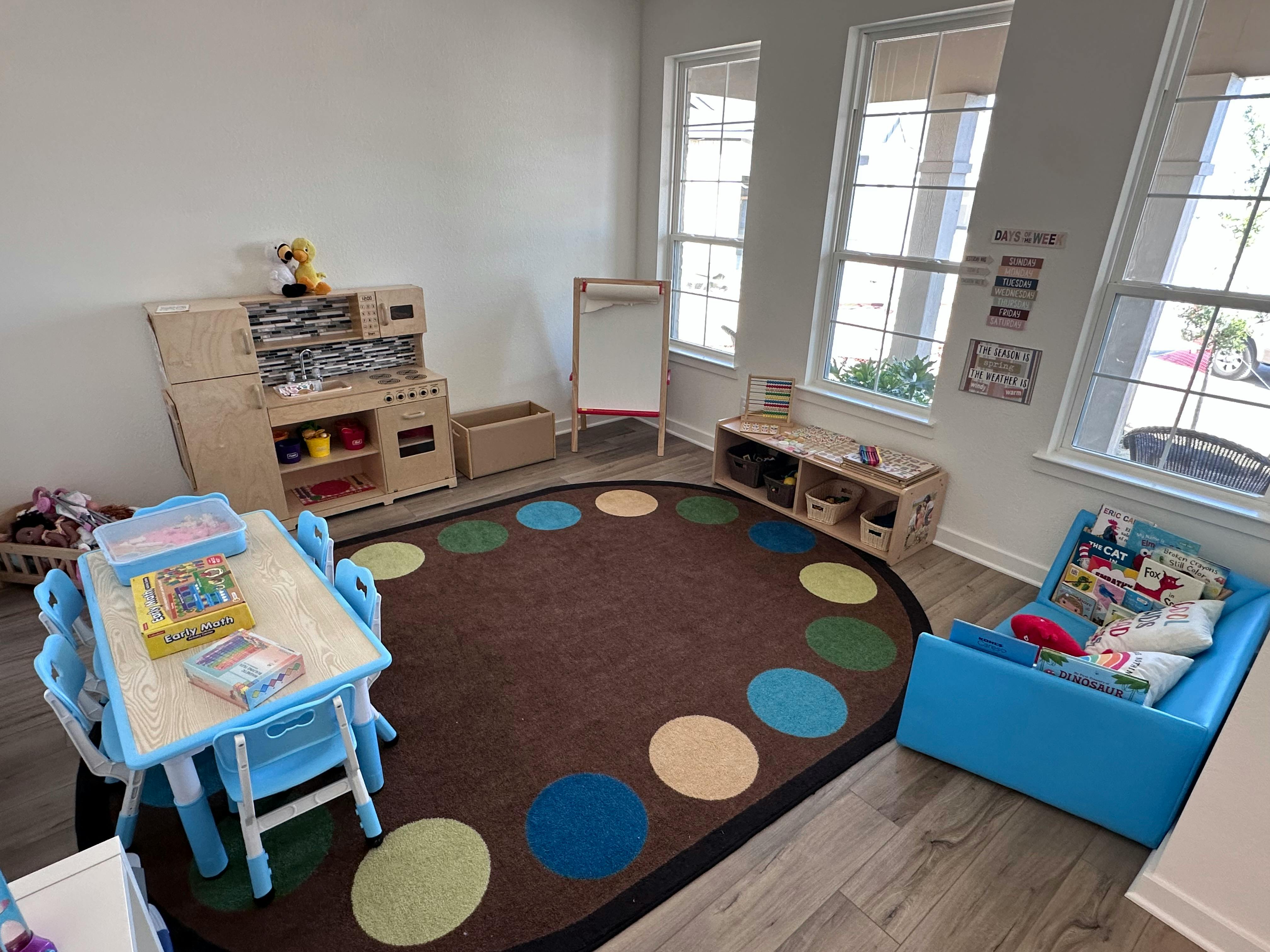 Playroom with a small table and chairs, play kitchen, and circular rug