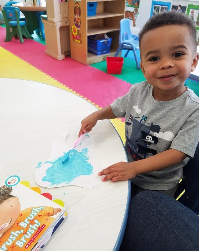 Child painting at a table in a classroom