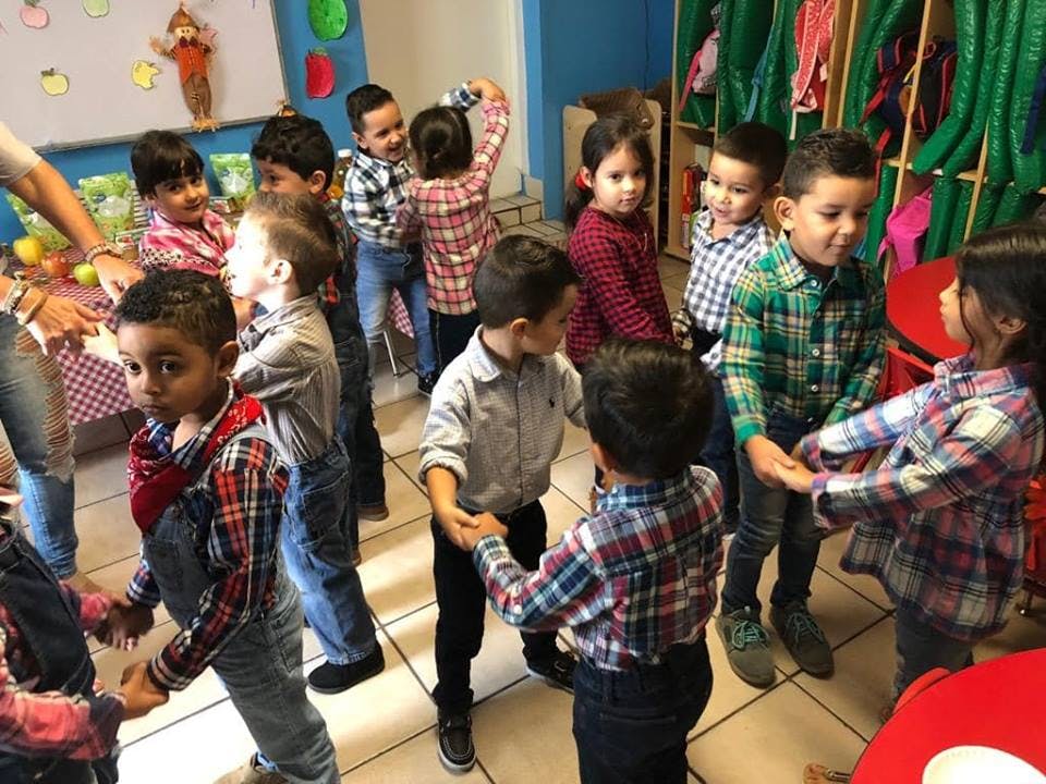 Children holding hands in a circle in a classroom