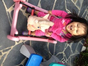 Child in a pink toy rocking horse