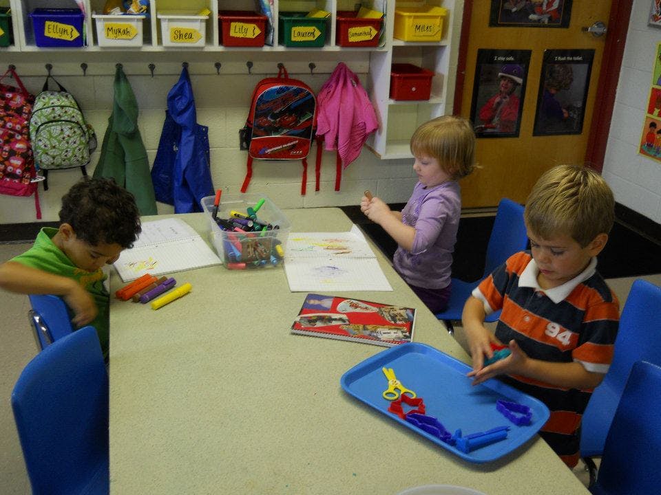 Three children at a table with art supplies in a classroom