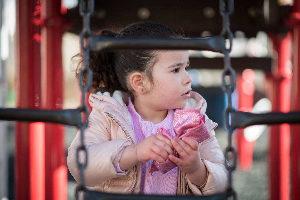 Child in a swing holding a pink cloth