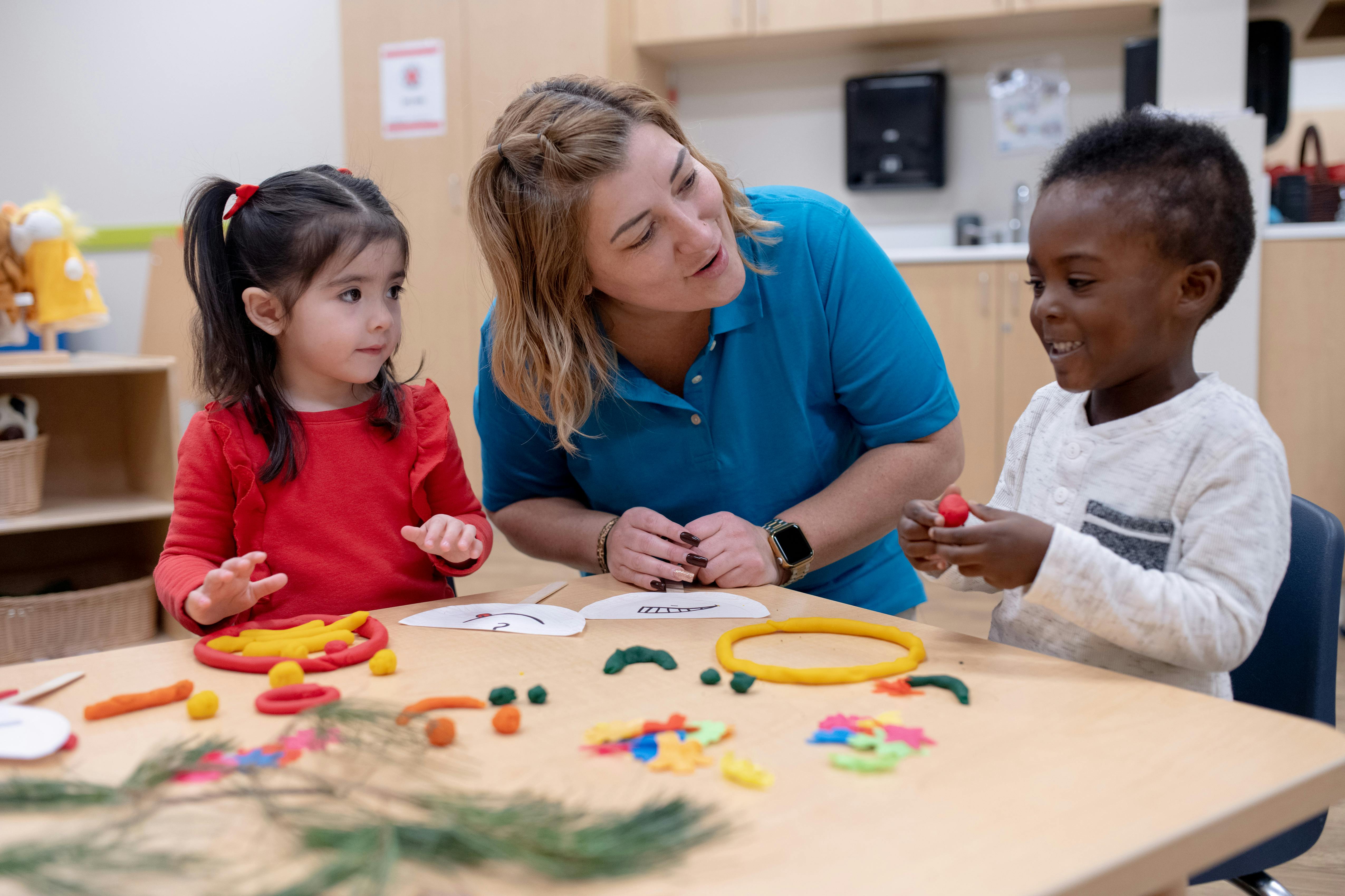 Adult and two children at a table with playdough and craft supplies