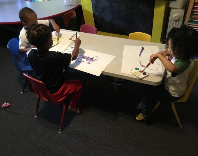 Three children painting at a table