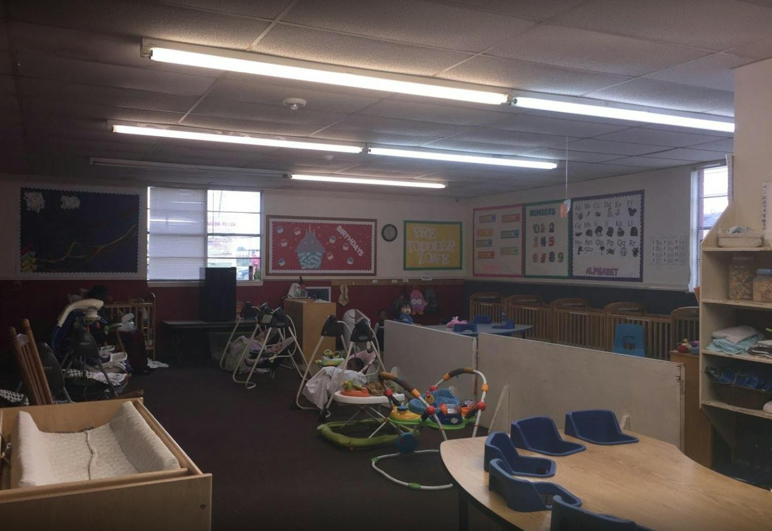 Daycare room with cribs, infant swings, and small tables