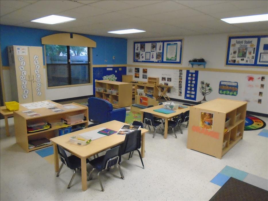 preschool classroom with small tables, chairs, and shelves