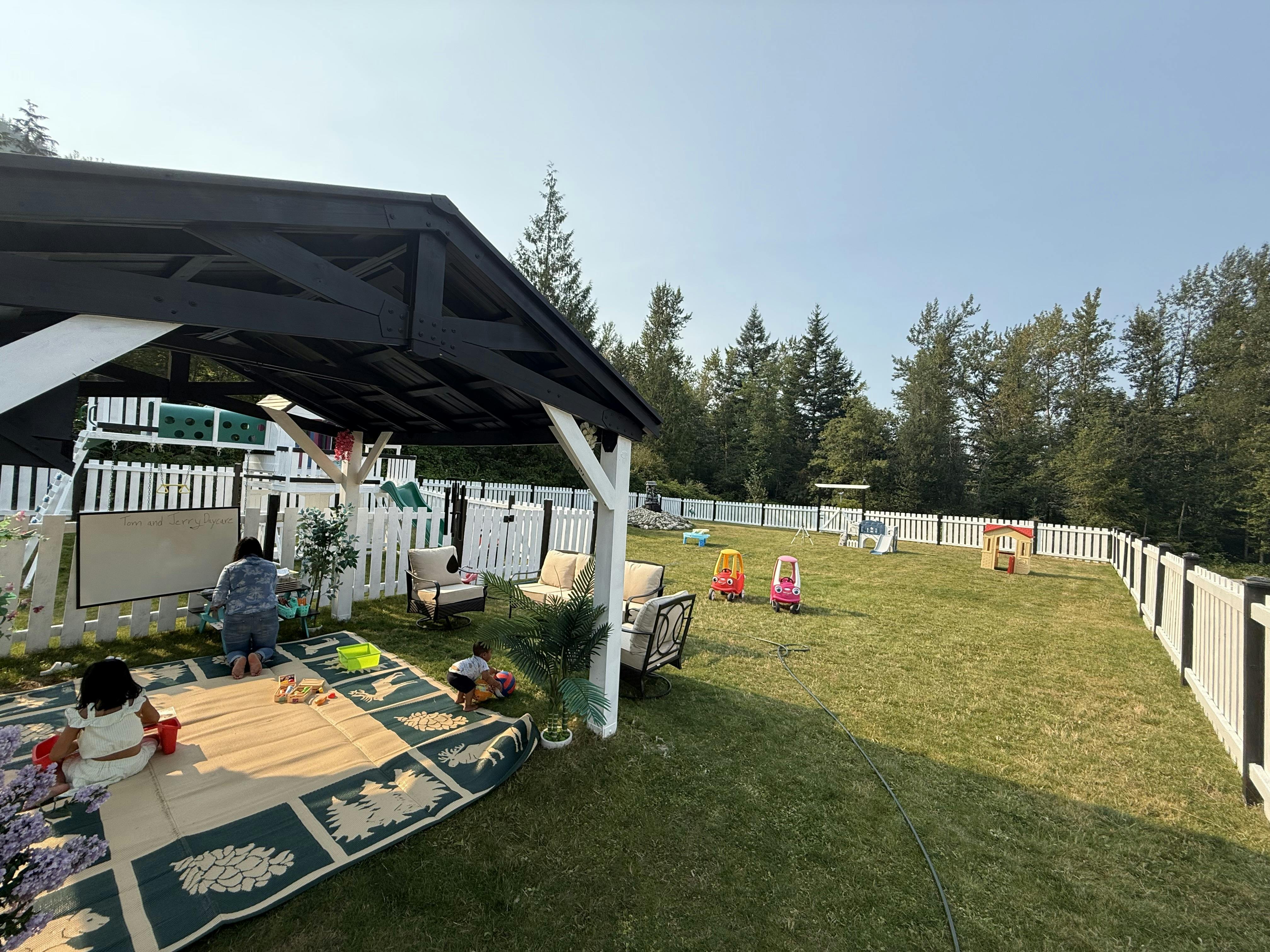People playing on a mat under a gazebo in a fenced yard