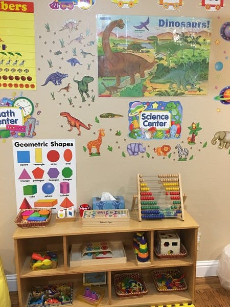 Classroom wall with dinosaur and animal decals, geometric shapes chart, and abacus