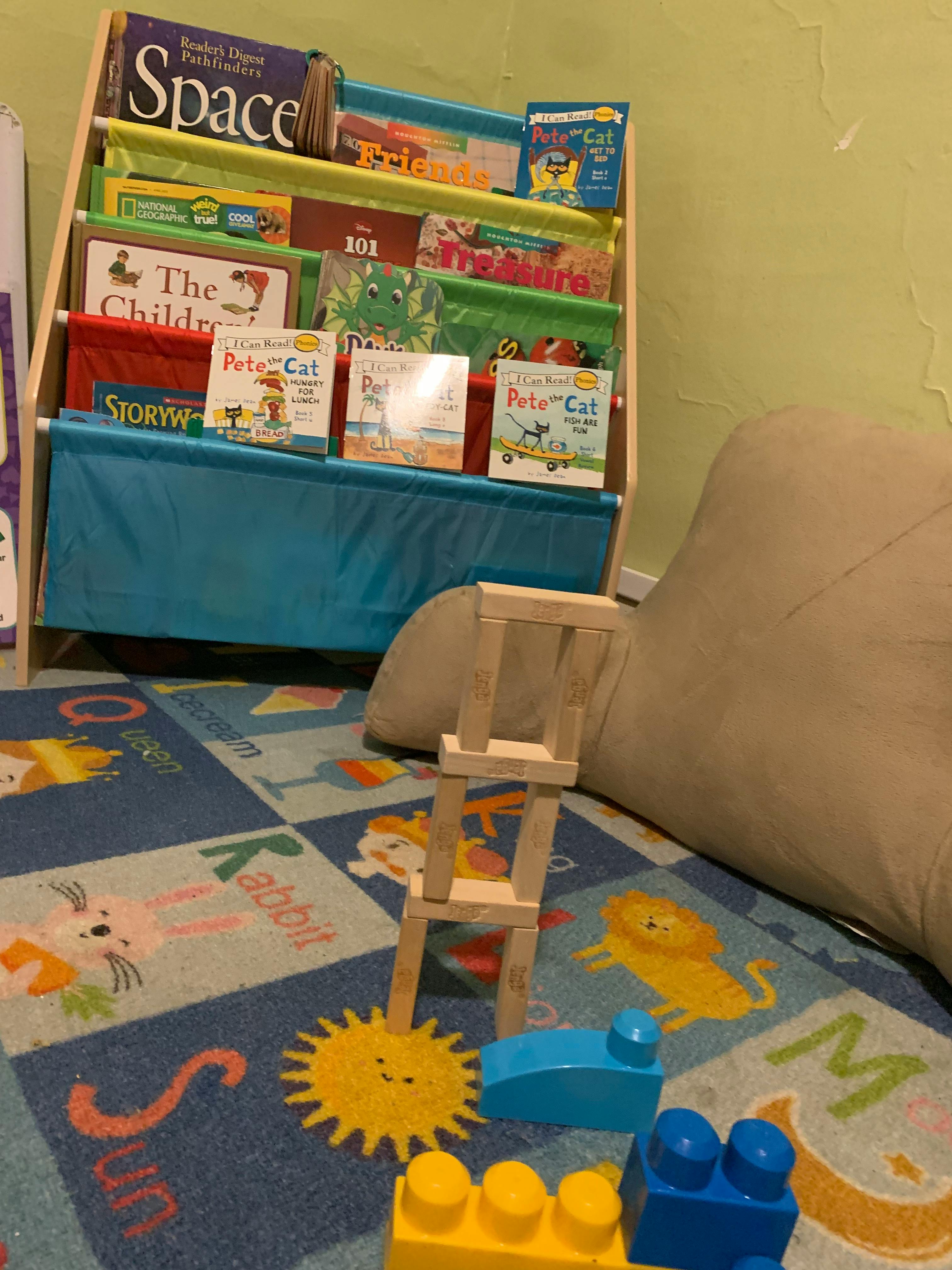 Children's book display with building blocks and a beanbag chair on a rug