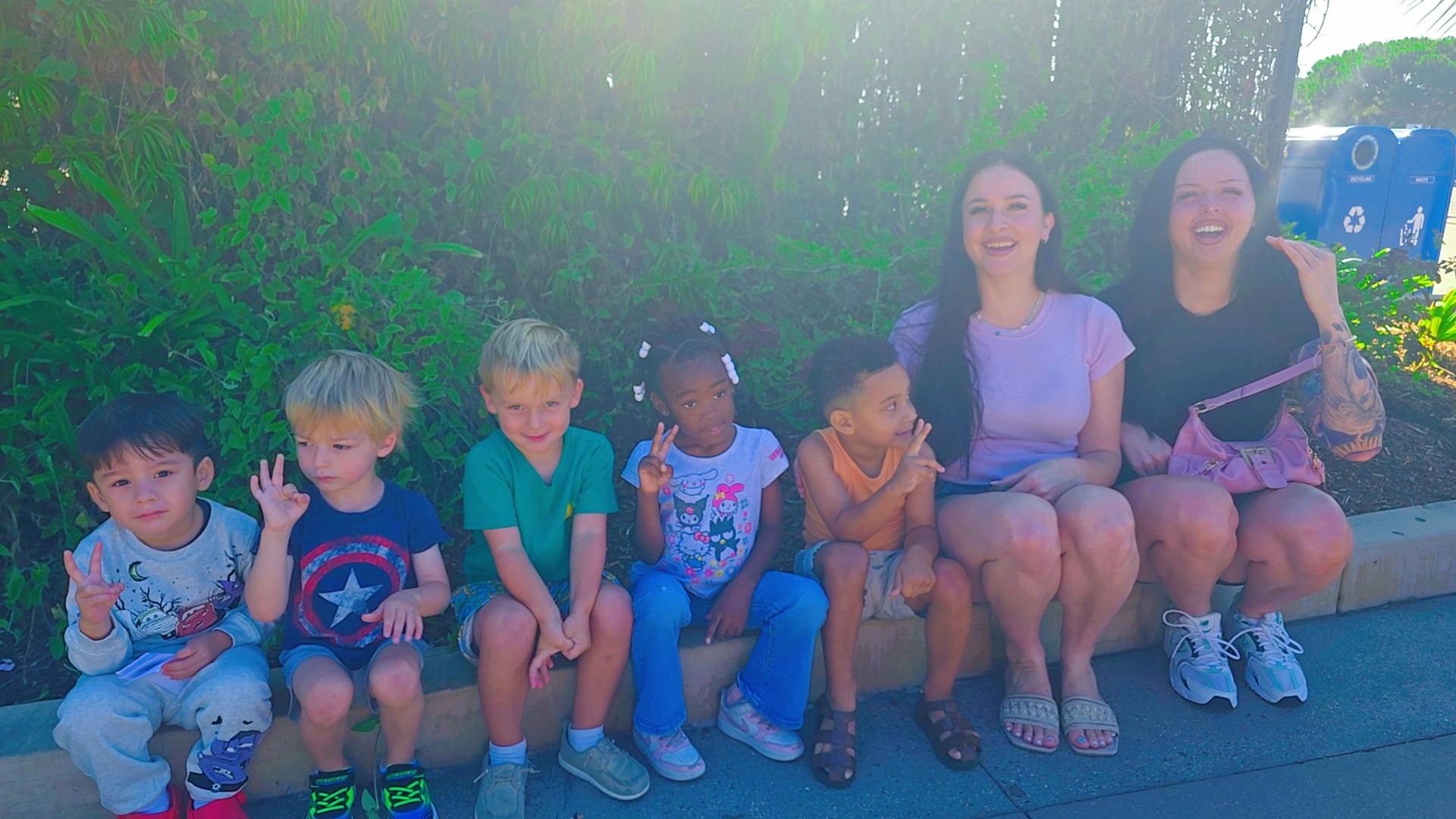 Group of children and two adults sitting together outdoors