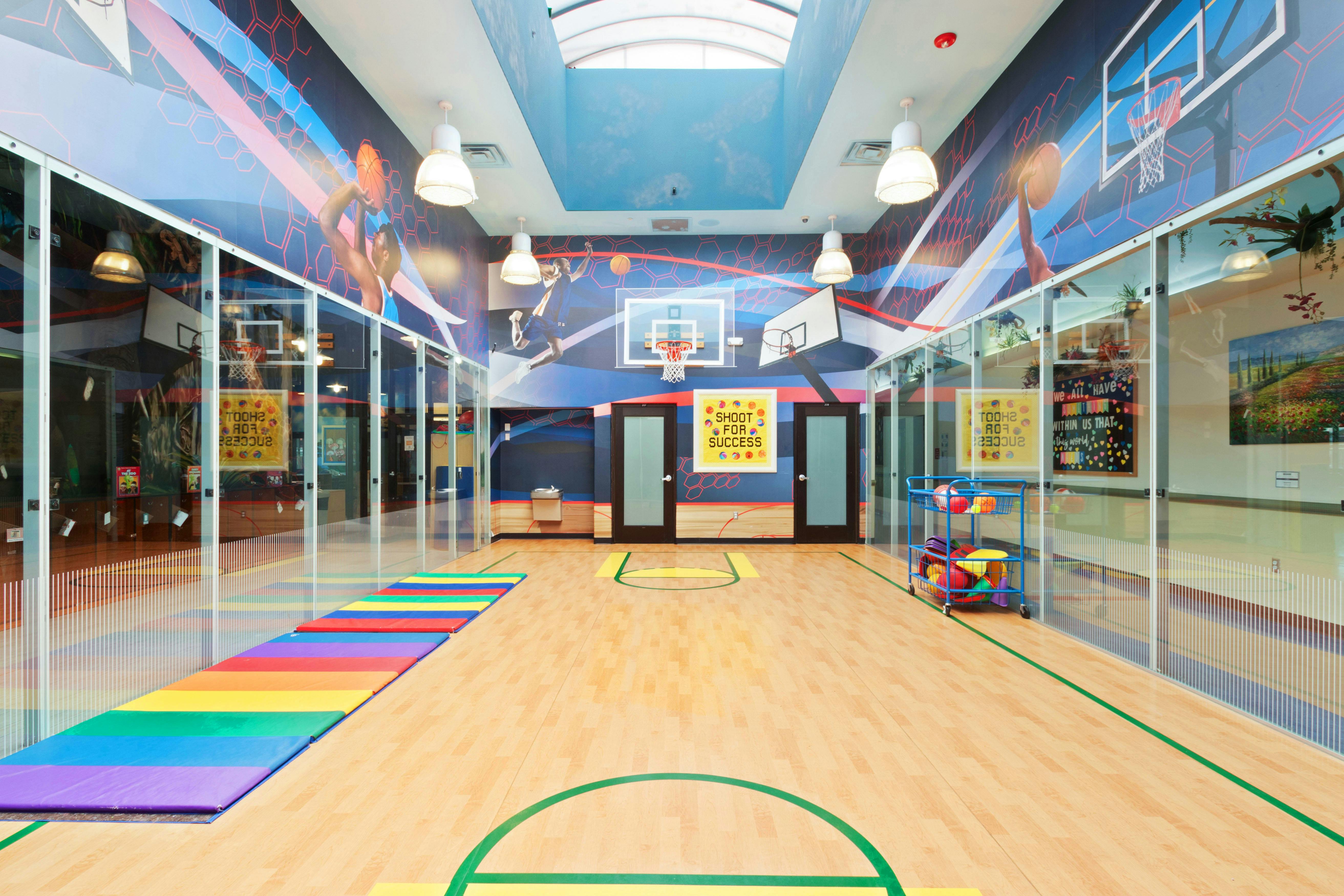 Indoor basketball court with colorful walls and a bright mural, a rainbow mat