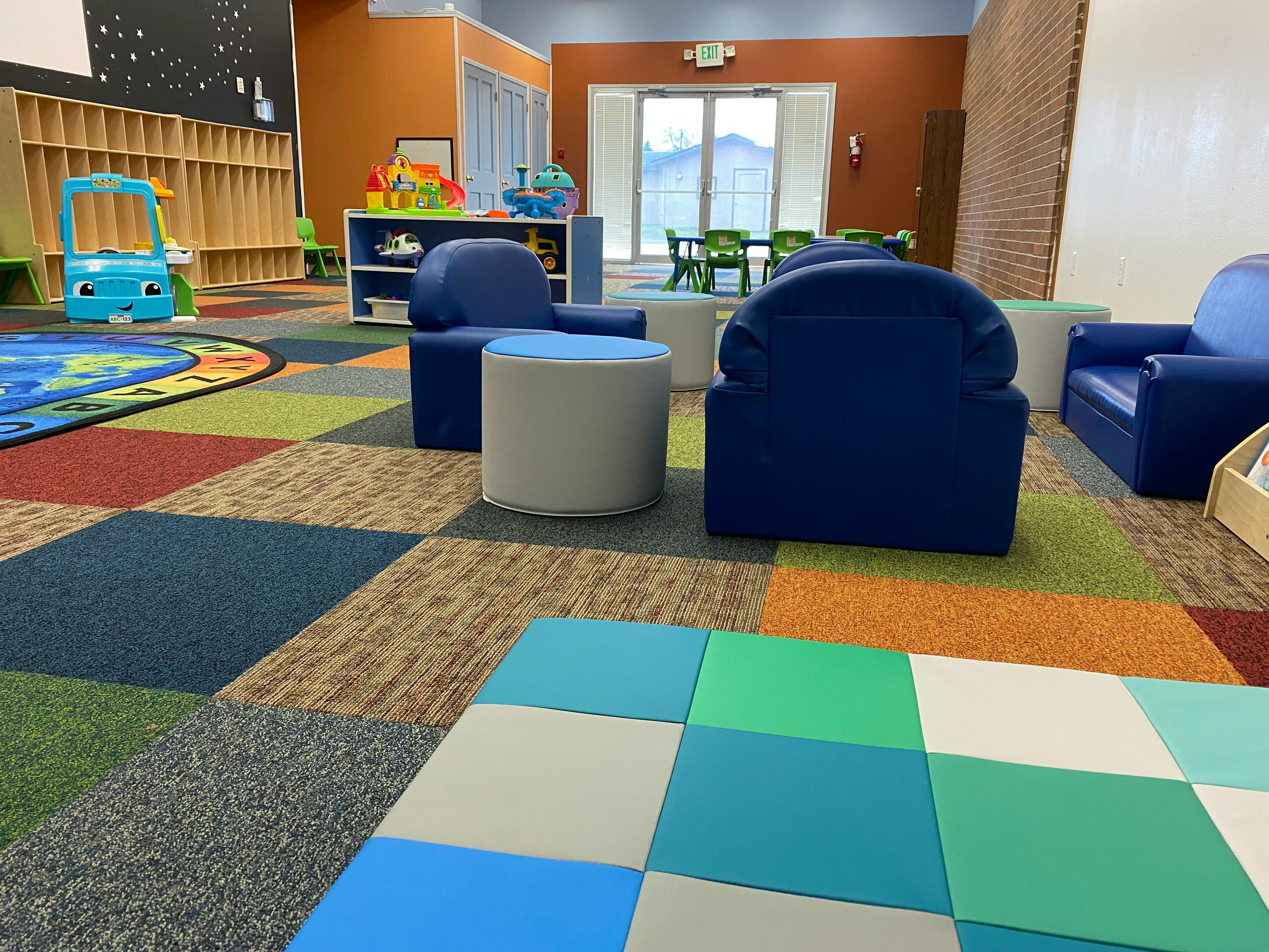 Playroom with blue chairs, colorful carpet, and toys
