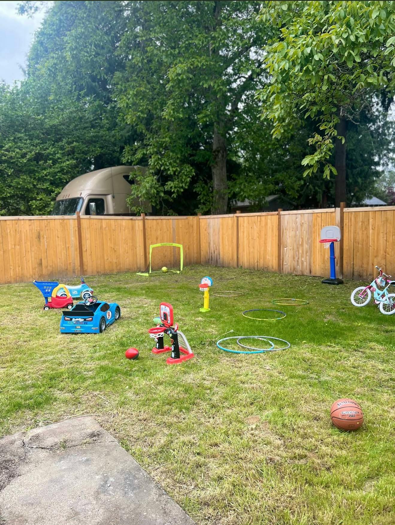 Backyard with various toys including a basketball, hoops, and a toy car