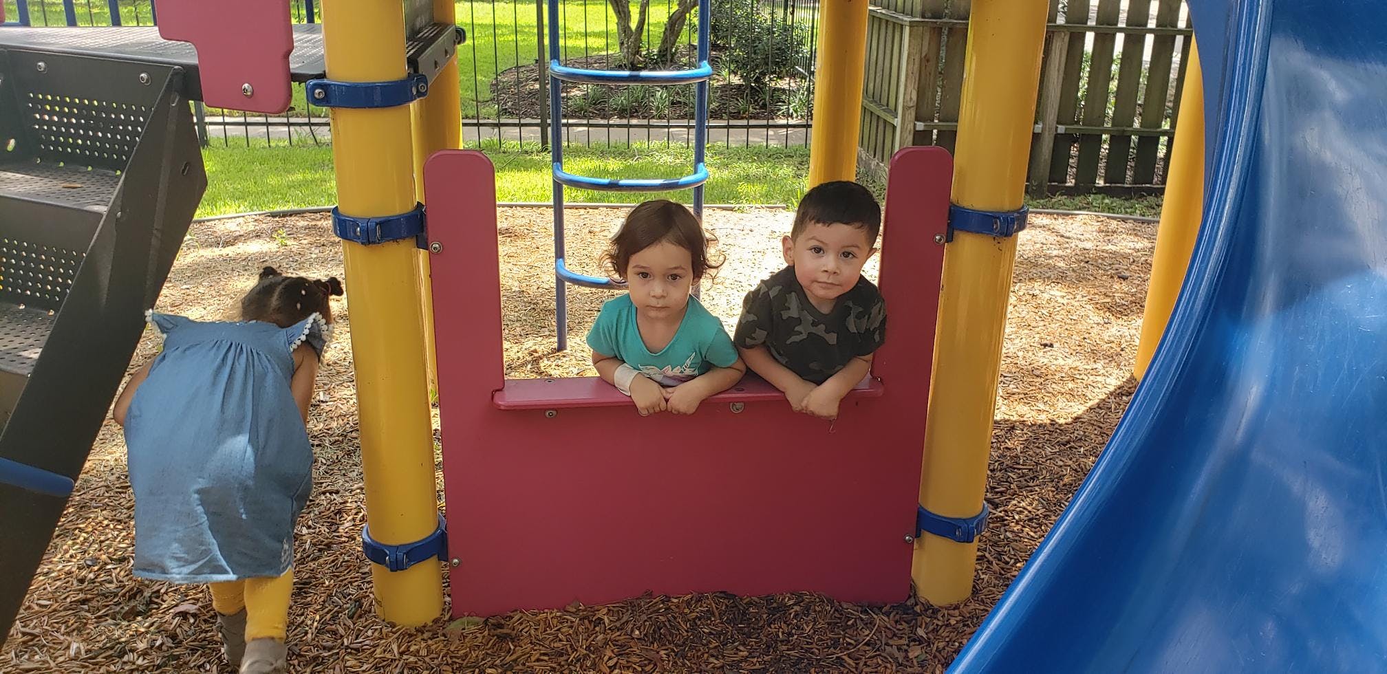 Two children looking over a red barrier on a playground