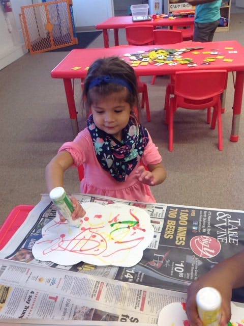 Child coloring a paper cutout with a marker