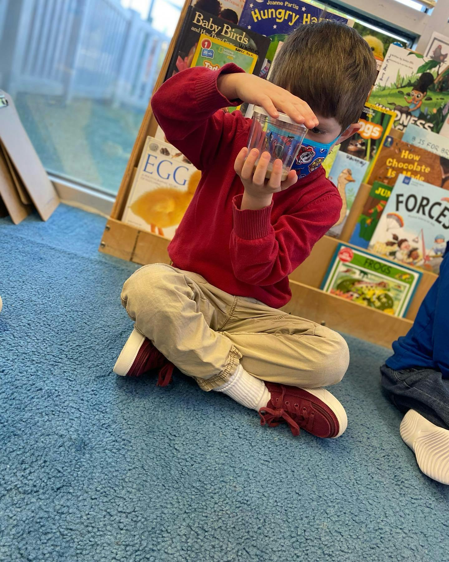 Child in a face mask holding a clear container