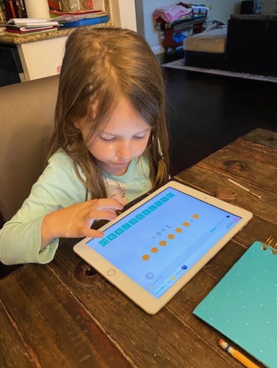 Child looking at a tablet on a wooden table