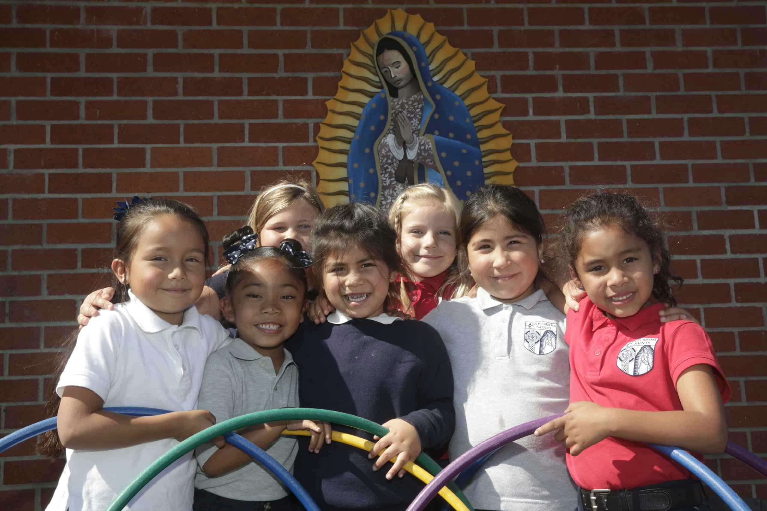 Group of diverse children posing with hula hoops in front of a brick wall