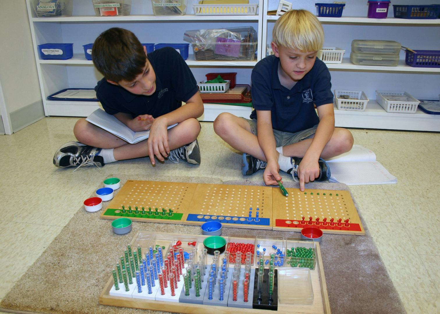 Two children sitting on the floor using math manipulatives