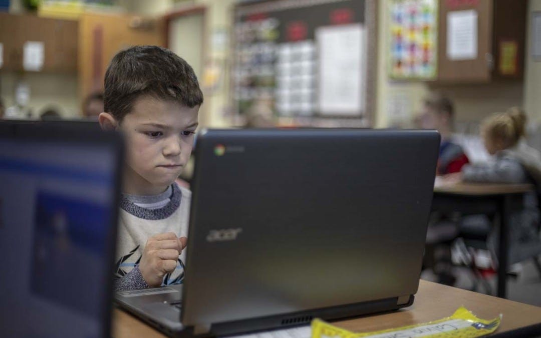 Child looking at a laptop in a classroom