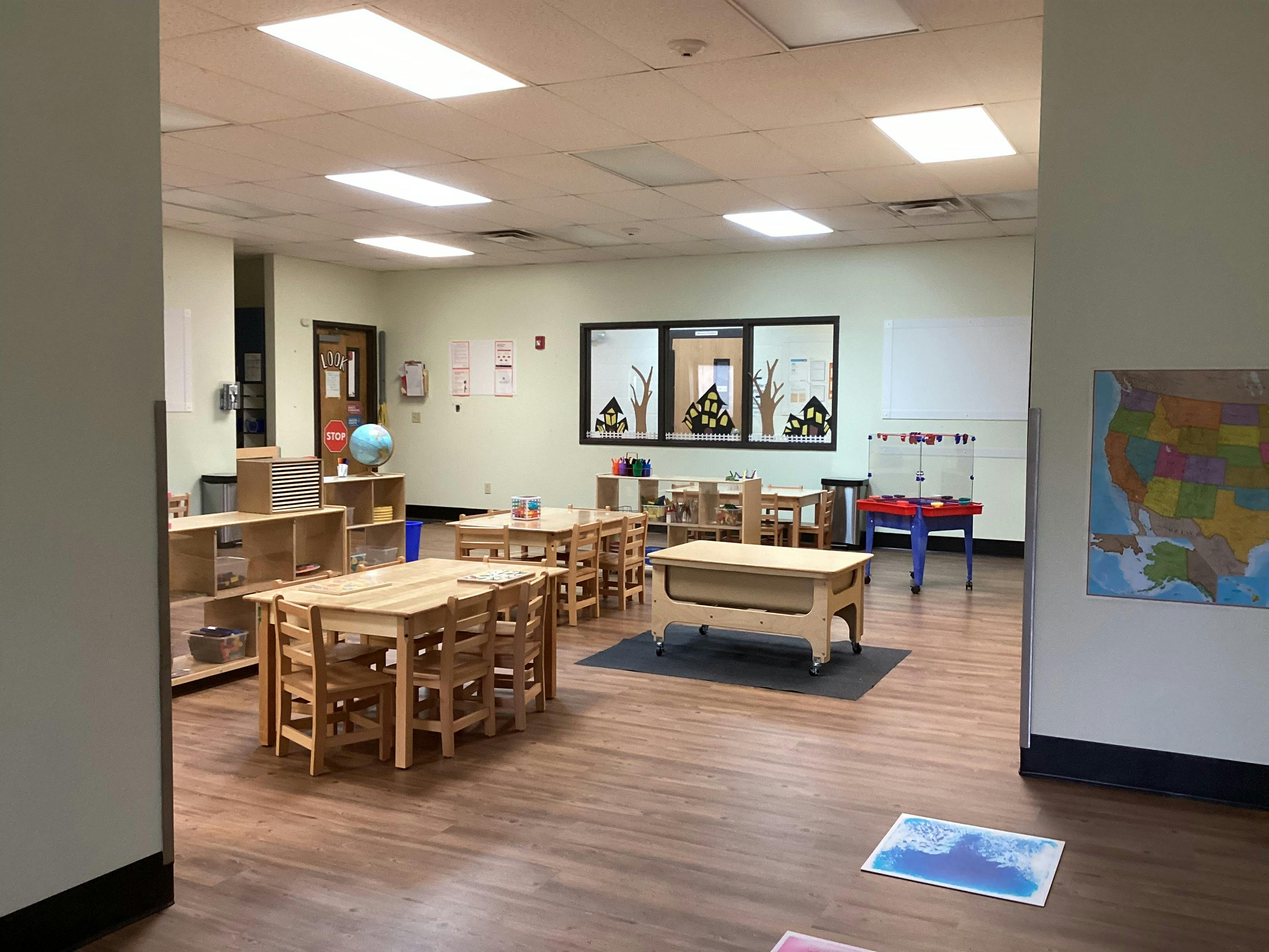 Classroom with wooden tables and chairs, a whiteboard, and a map