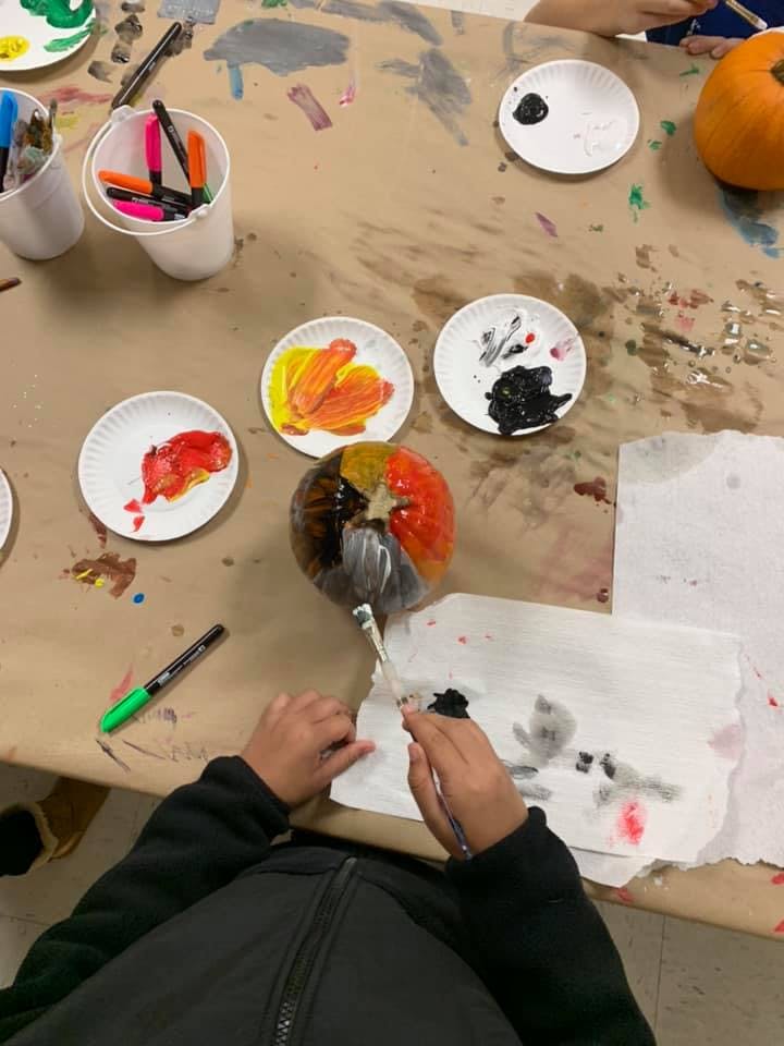 Person painting a pumpkin with multiple colors