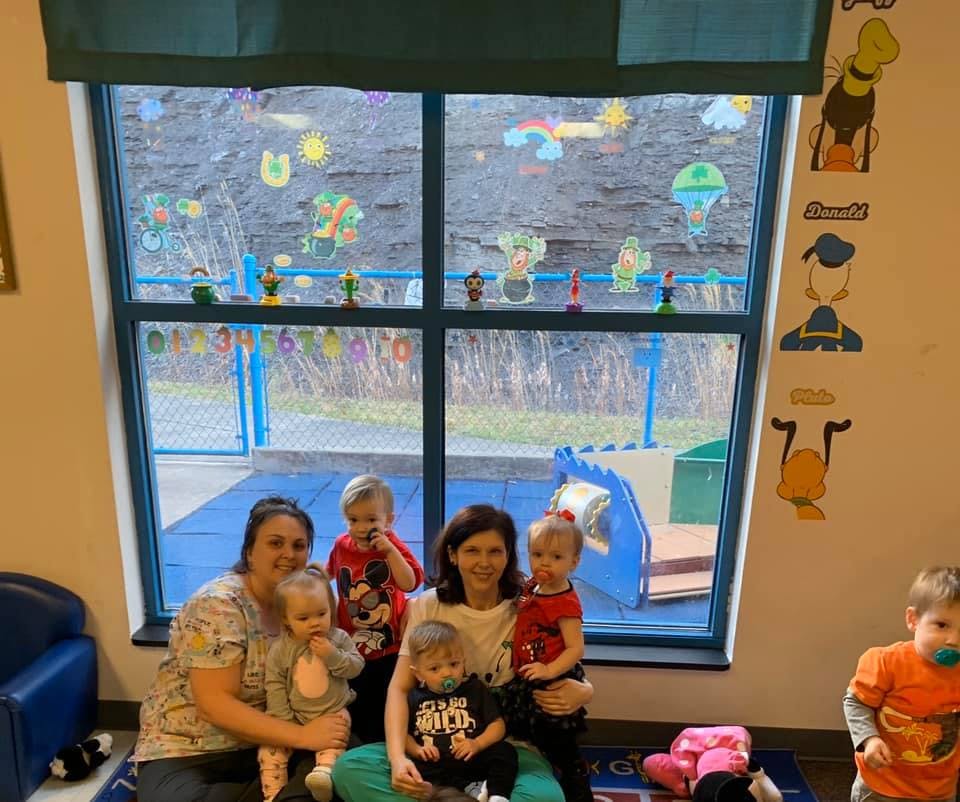 Two people with five children in a room with a large window