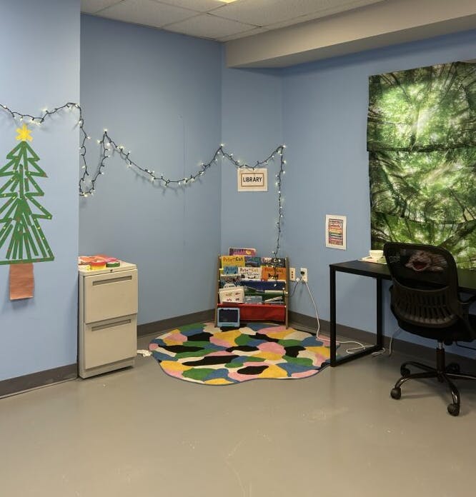 Room with string lights, a Christmas tree drawing, and a sign that says "LIBRARY"