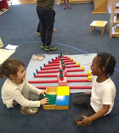 Two children playing with colorful learning materials on the floor