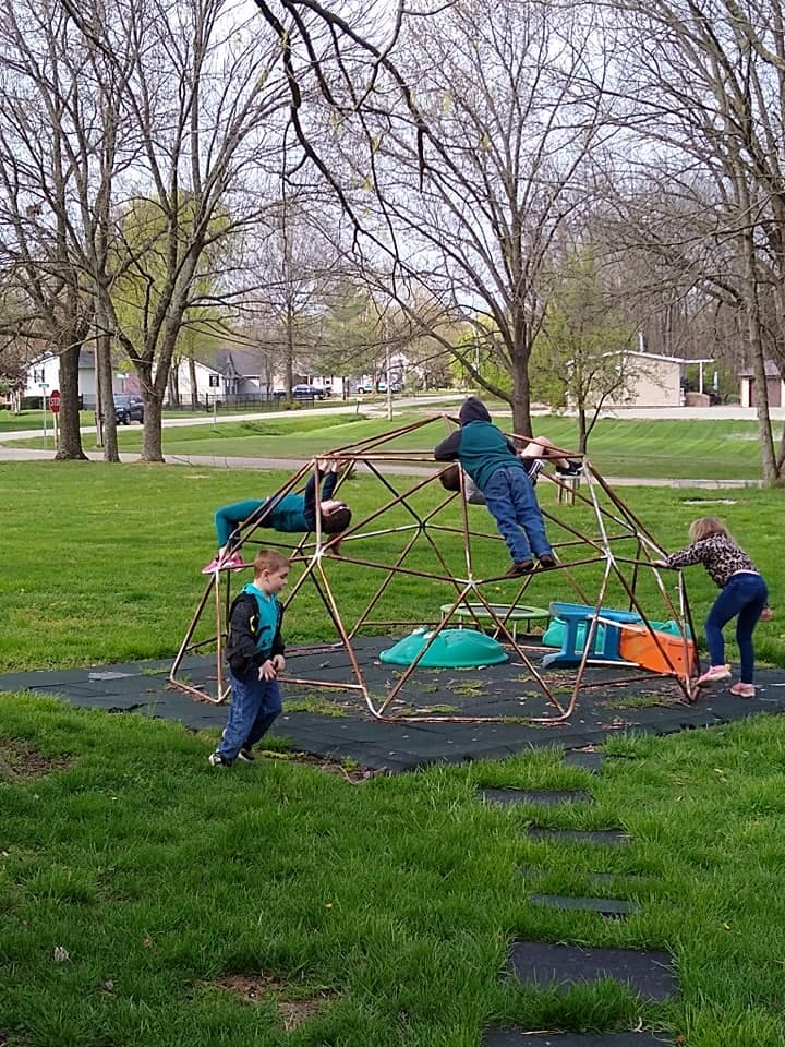 Children playing on a geodesic dome climber in a park
