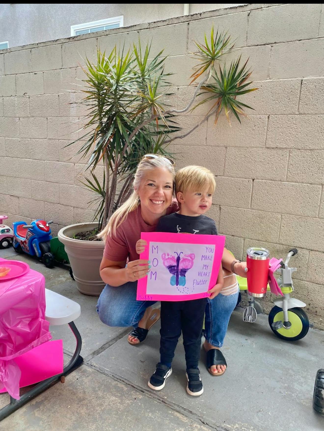 Adult and child holding a handmade card with butterfly art that says Mom