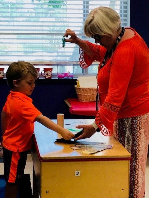 Adult and child interacting at a table in a classroom