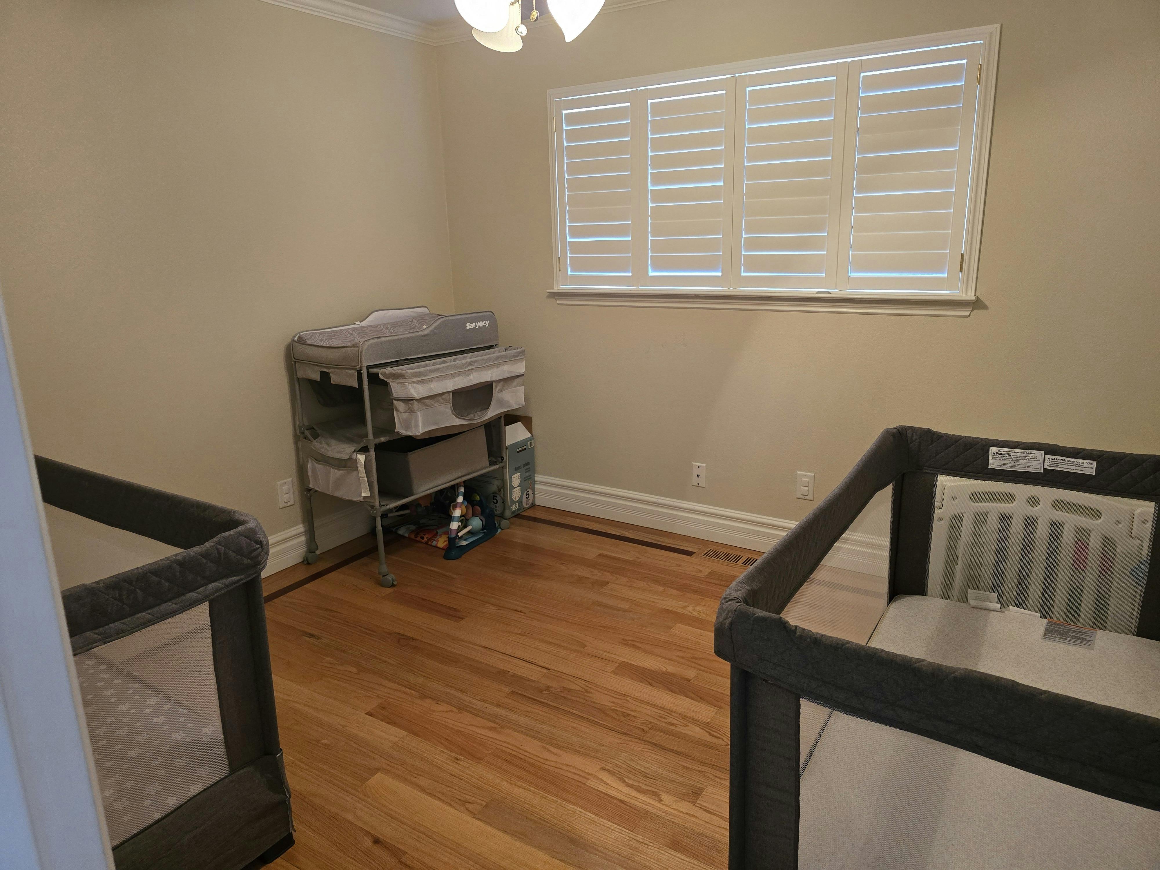 Two baby cribs and a changing table in a nursery room